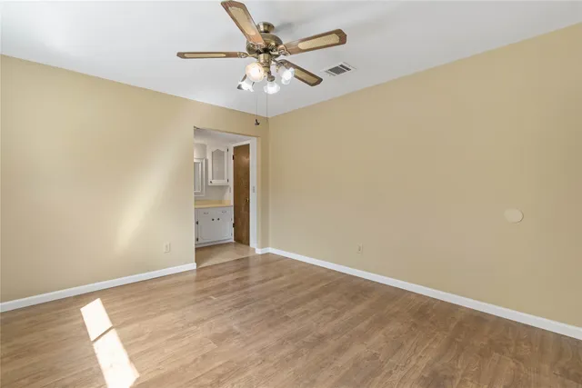 an empty room with a ceiling fan and wooden floor