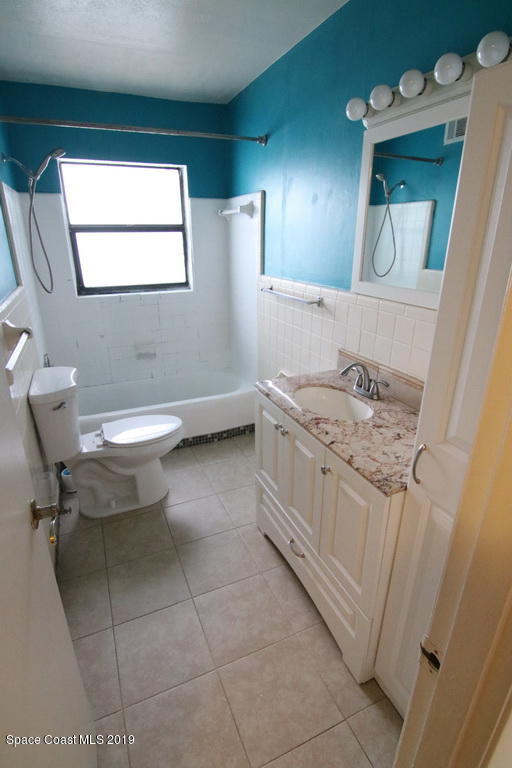 945 Trinidad Road Cocoa Beach, FL 32931 - Photo 15 of 34 a bathroom with a granite countertop sink toilet a mirror and bathtub