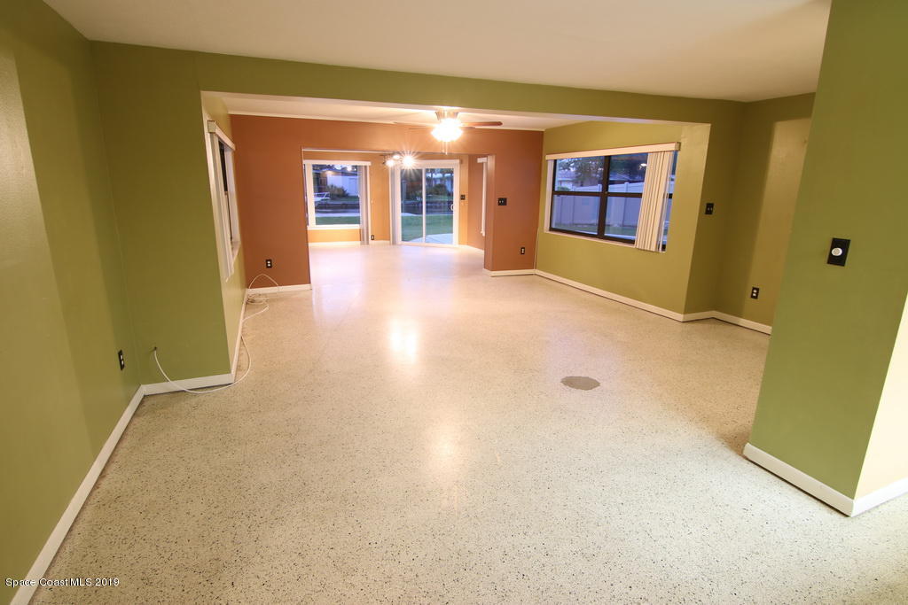 945 Trinidad Road Cocoa Beach, FL 32931 - Photo 8 of 34 an empty room with chandelier fan and windows