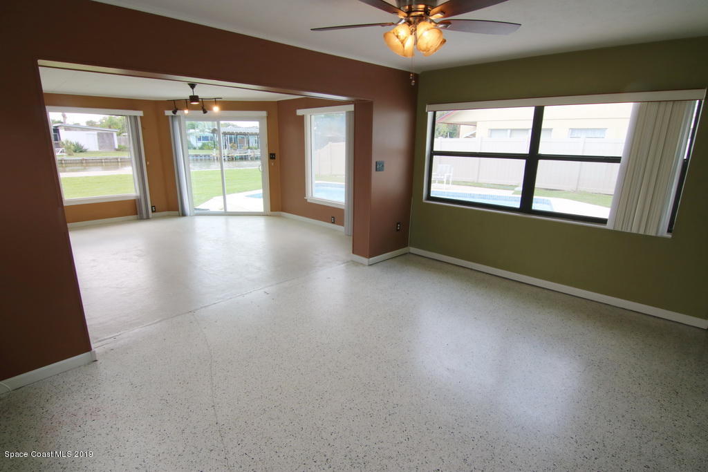 945 Trinidad Road Cocoa Beach, FL 32931 - Photo 9 of 34 an empty room with chandelier fan and windows