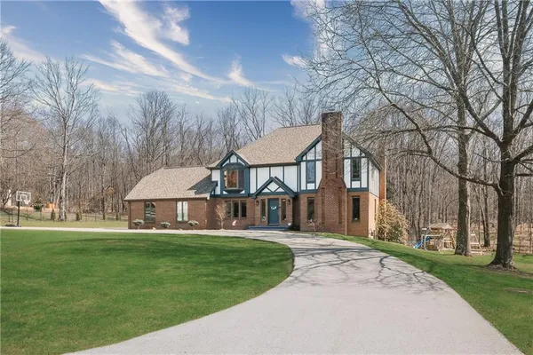 a view of a big house with a big yard and large trees
