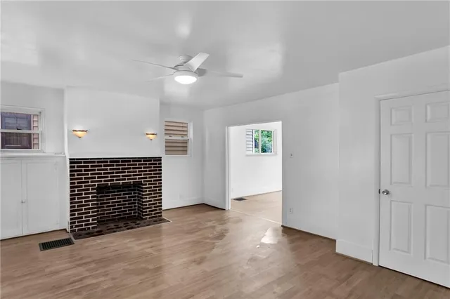 an empty room with wooden floor cabinet and windows