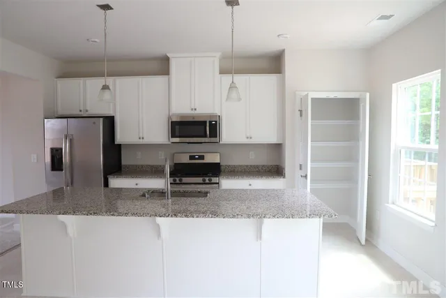 a kitchen with kitchen island a sink stainless steel appliances and a counter top space