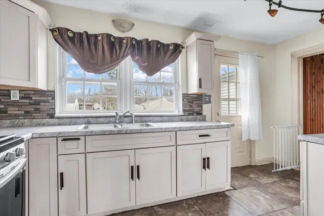 a kitchen with stainless steel appliances granite countertop a sink a window and cabinets