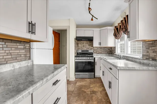 a kitchen with stainless steel appliances granite countertop a stove a sink and a refrigerator