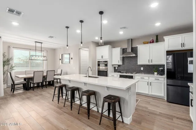 a large kitchen with cabinets chairs and wooden floor