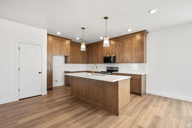 1661 West Ross Road Syracuse, UT 84075 - Photo 8 of 28 Kitchen featuring wood finish cabinets, decorative light fixtures, dark wood-type flooring, a kitchen island with sink, and stainless steel range with electric cooktop