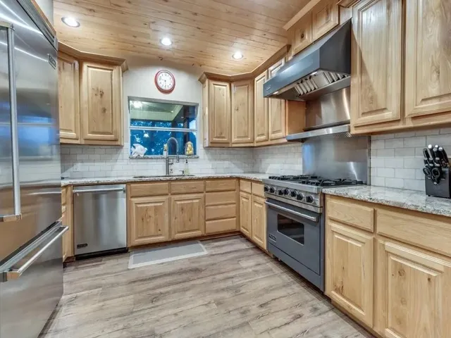 a dining room with stainless steel appliances kitchen island granite countertop a table chairs and a refrigerator