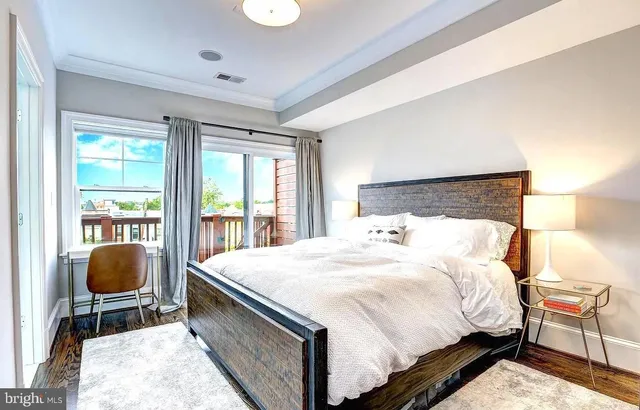 a bedroom with a bed a desk and chair with wooden floor