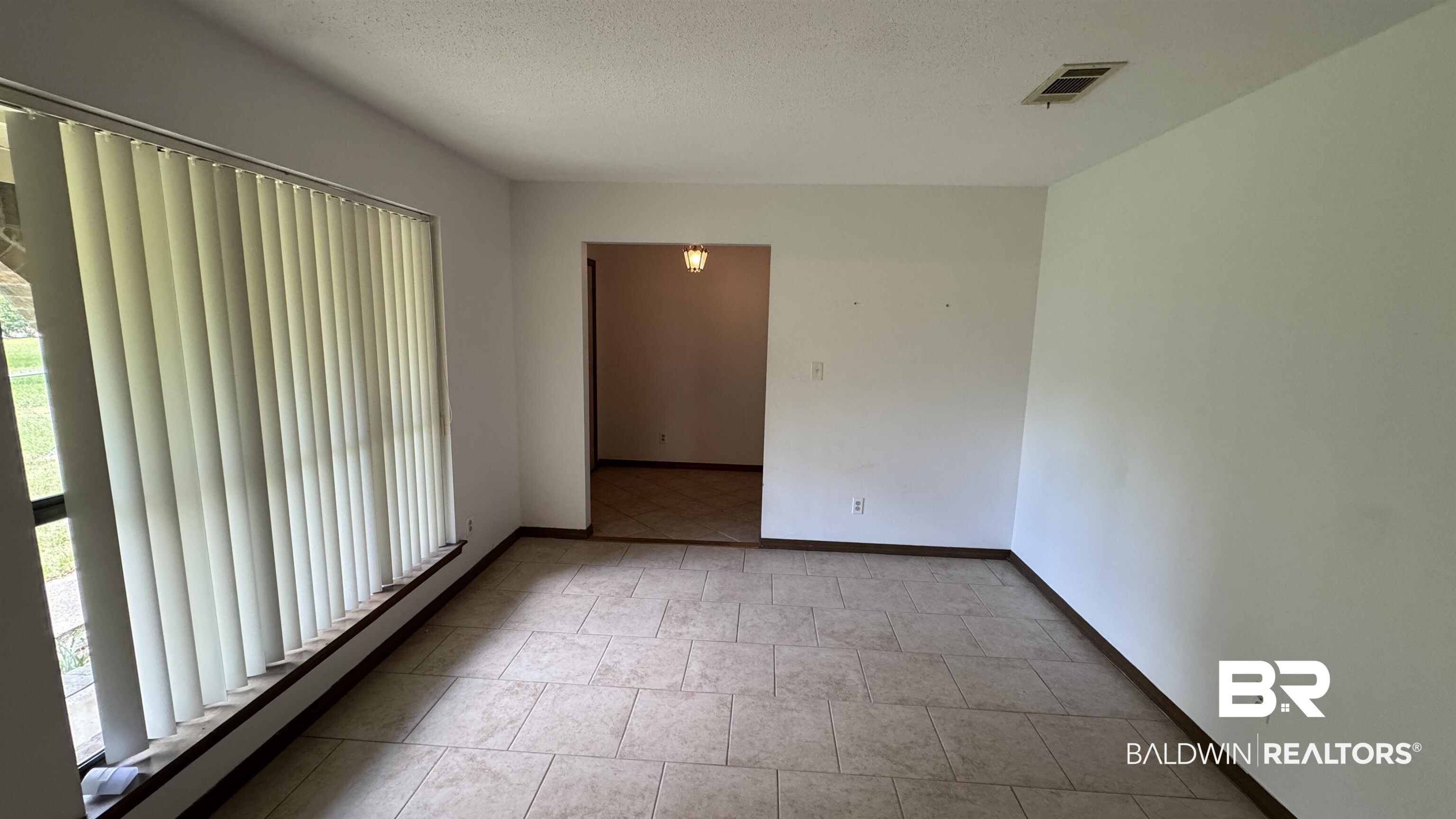 33370 Highway 98 Lillian, AL 36549 - Photo 21 of 58 Spacious room featuring neutral tile flooring, white painted walls, and a large window with vertical blinds