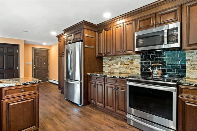 a kitchen with stainless steel appliances granite countertop wooden cabinets a sink and a large window