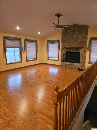 a view of an empty room with wooden floor and a fireplace