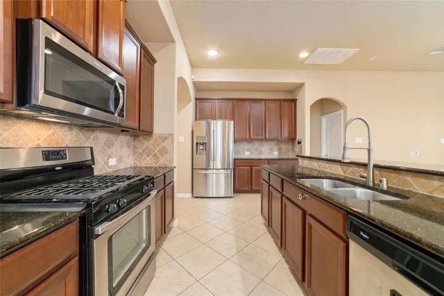 a kitchen with granite countertop a sink stainless steel appliances and cabinets