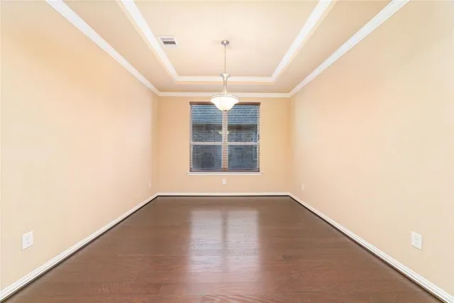 an empty room with wooden floor chandelier and windows