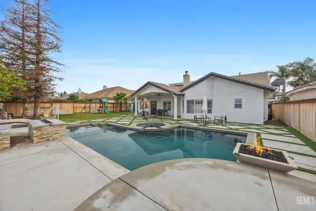 a view of swimming pool with outdoor seating and house in the background