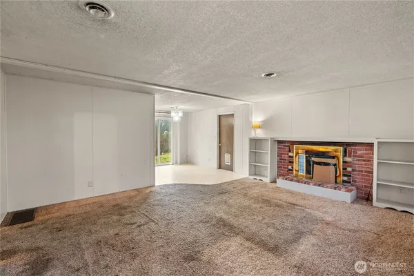 a view of an empty room with a fireplace and a window