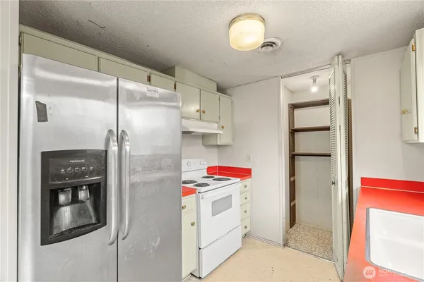 a kitchen with a refrigerator and white cabinets