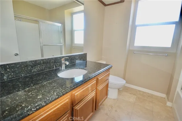a bathroom with a granite countertop sink and a toilet