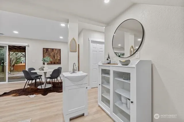 a living room with furniture a mirror a clock and a view of kitchen
