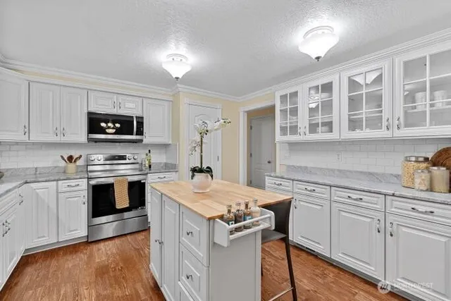 a kitchen with granite countertop a stove a sink dishwasher and a refrigerator with wooden floor