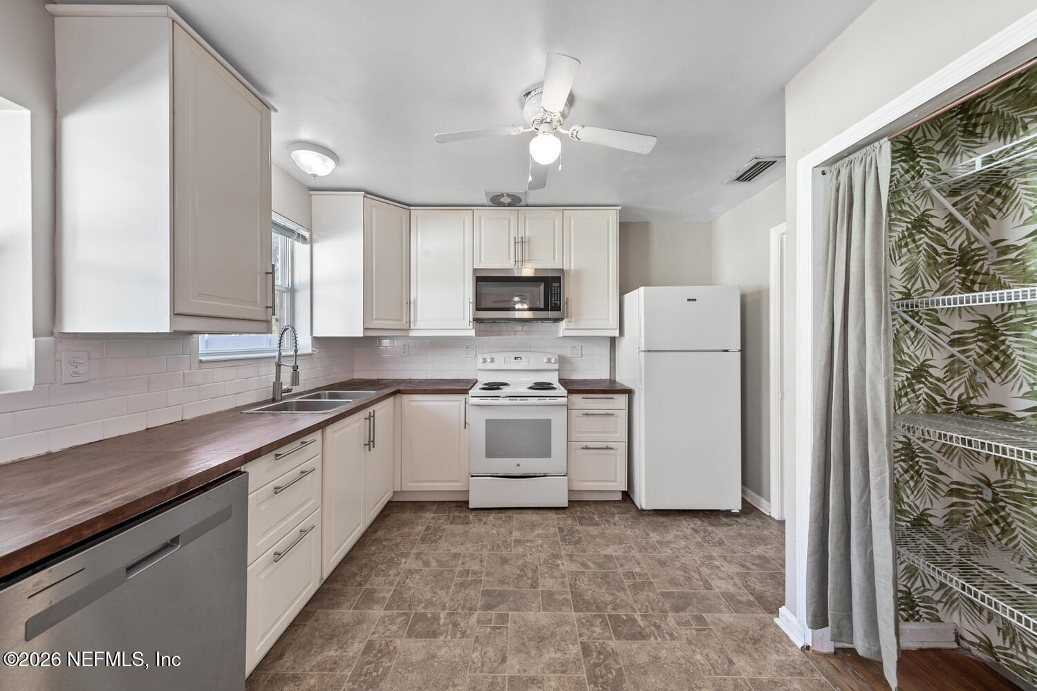 8309 Calento Street Jacksonville, FL 32211 - Photo 11 of 25 a kitchen with white cabinets and white appliances