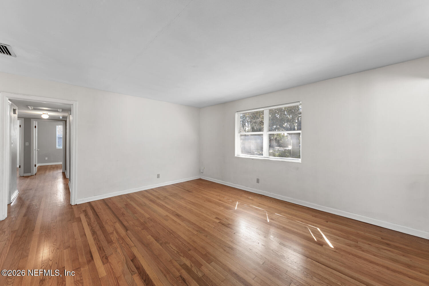 8309 Calento Street Jacksonville, FL 32211 - Photo 7 of 25 a view of an empty room with wooden floor and a window