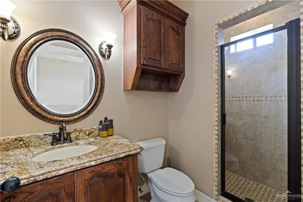 a bathroom with a granite countertop toilet a sink and a mirror