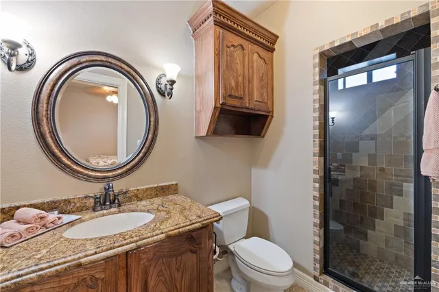 a bathroom with a granite countertop toilet a sink and a mirror