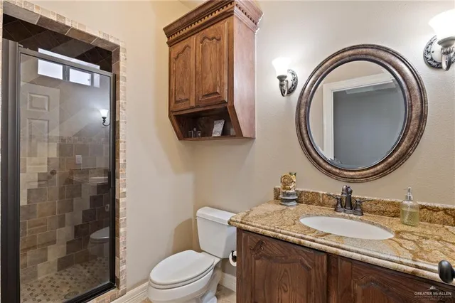 a bathroom with a granite countertop toilet a sink and a mirror