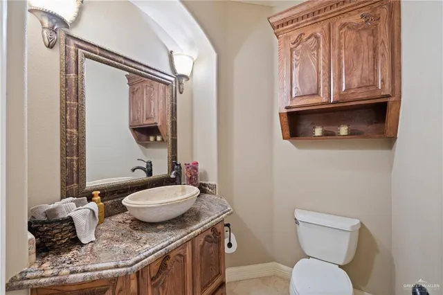 a bathroom with a granite countertop toilet sink and mirror