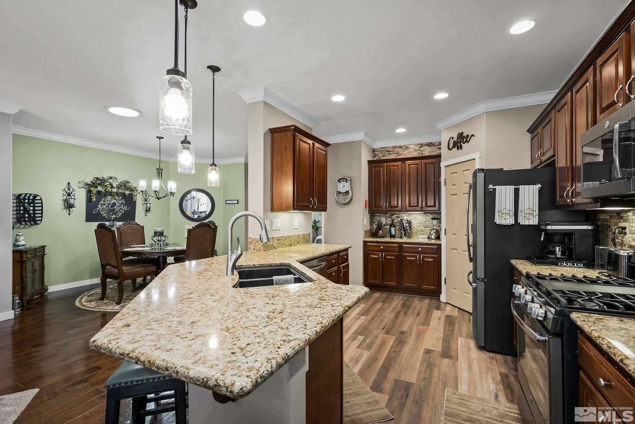 7615 Crest Bluff Drive Reno, NV 89506 - Photo 8 of 32 a kitchen with stainless steel appliances granite countertop a stove top oven a refrigerator a sink and chairs