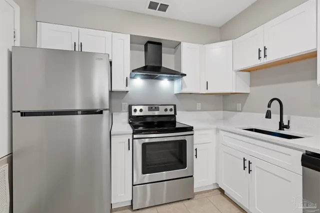 a kitchen with granite countertop a refrigerator sink and cabinets