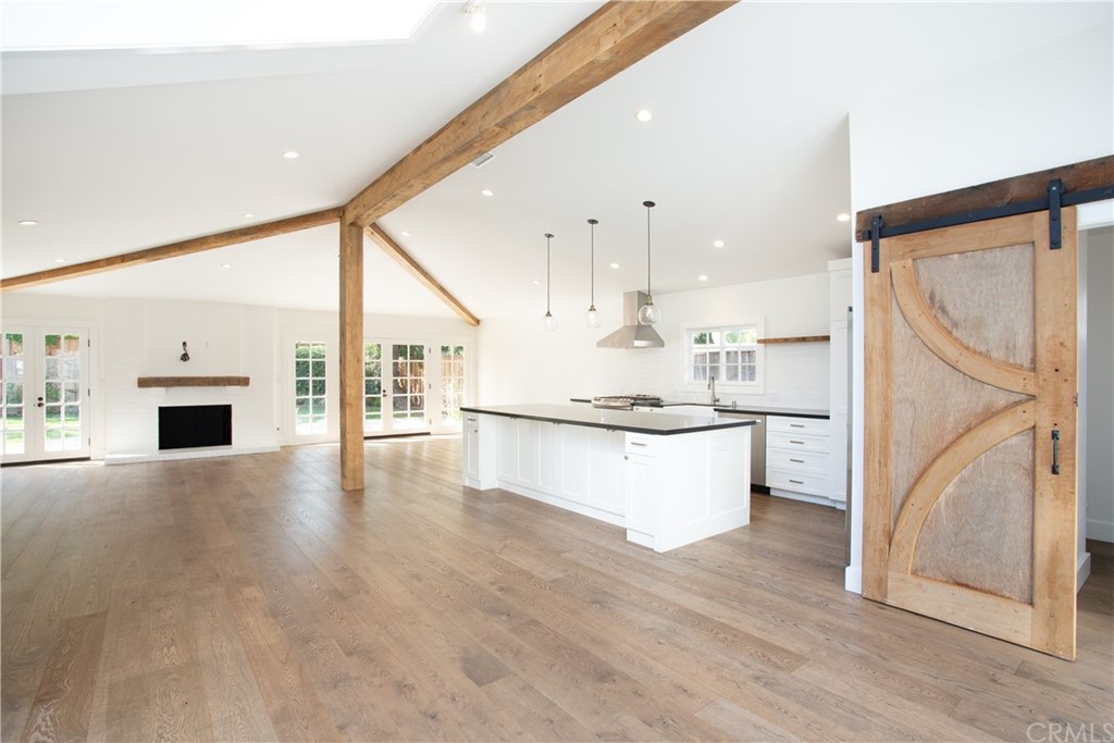 1921 Mariners Drive Newport Beach, CA 92660 - Photo 3 of 17 a large white kitchen with kitchen island a sink a stove and white cabinets with wooden floor
