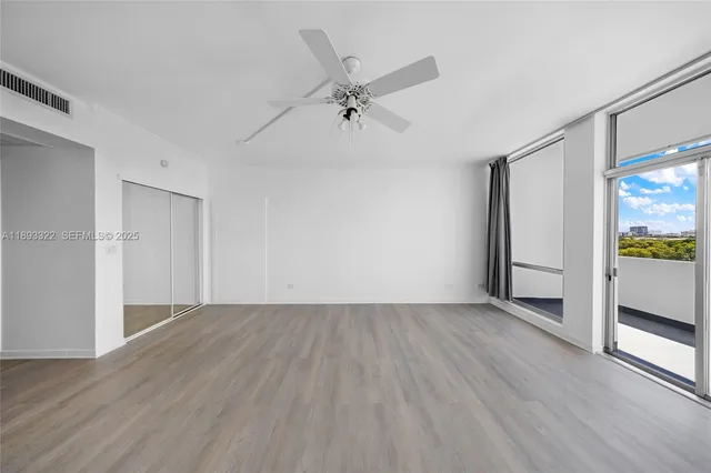 an empty room with wooden floor and a ceiling fan