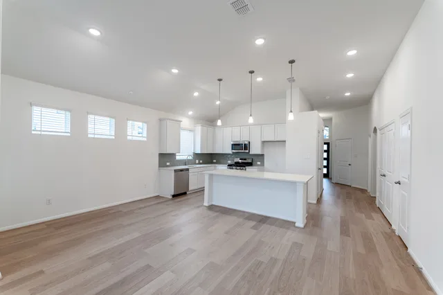 a view of kitchen with kitchen island stainless steel appliances refrigerator stove microwave and cabinets