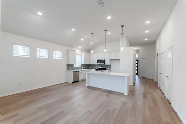 a view of kitchen with kitchen island stainless steel appliances refrigerator stove microwave and cabinets