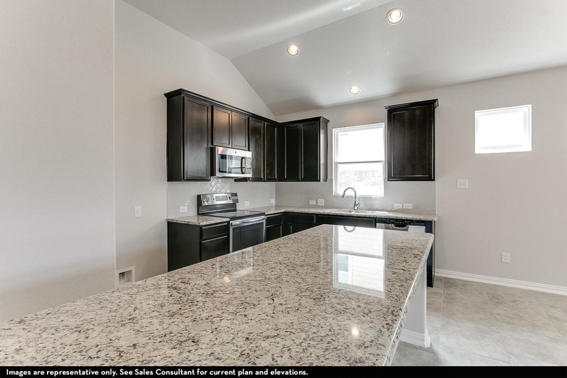 265 Rubber Tree Way Buda, TX 78610 - Photo 5 of 11 a kitchen with stainless steel appliances granite countertop a sink stove and microwave