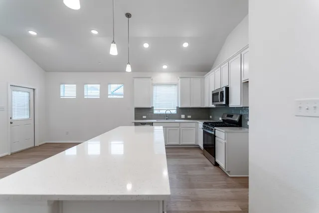 a large white kitchen with kitchen island a sink a stove a refrigerator and white cabinets