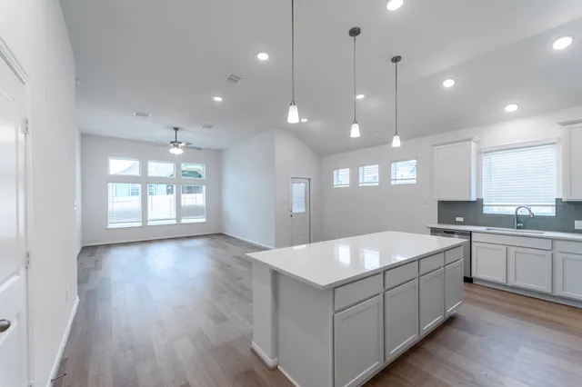 a large white kitchen with a large island oven a sink stainless steel appliances and a center island