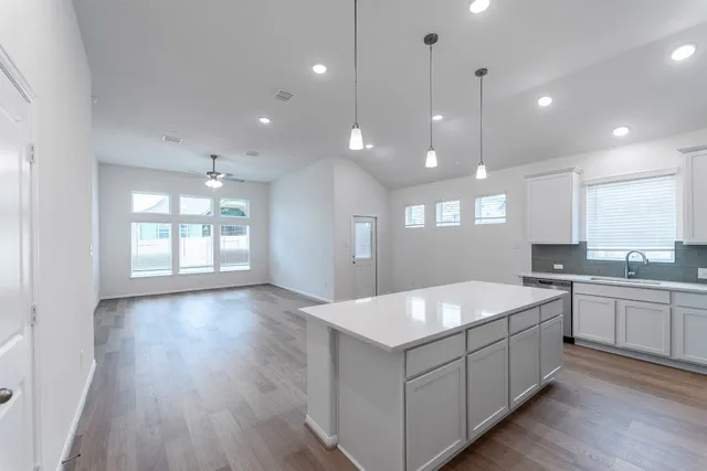 a large white kitchen with a large island oven a sink stainless steel appliances and a center island