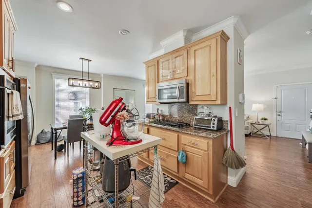 a kitchen with stainless steel appliances granite countertop a stove top oven a dining table and chairs with wooden floor