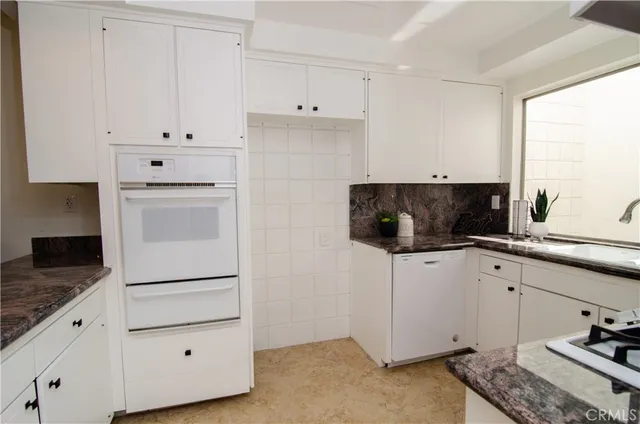 a kitchen with granite countertop white cabinets and white appliances