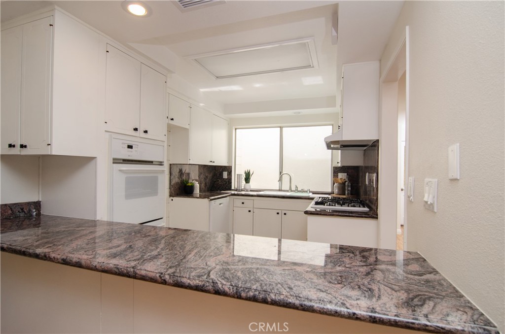 26701 Oak Branch Circle Newhall, CA 91321 - Photo 15 of 44 a kitchen with stainless steel appliances granite countertop a sink stove and white cabinets