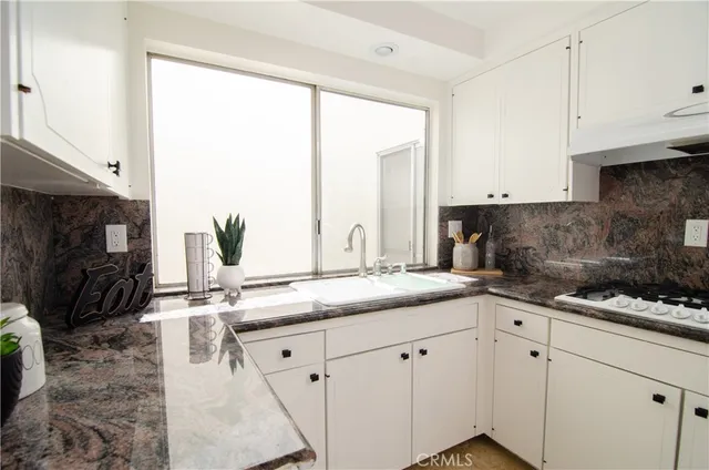 a kitchen with stainless steel appliances granite countertop a sink a stove and white cabinets