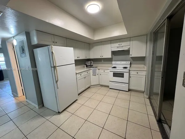a kitchen with white cabinets a refrigerator and a stove