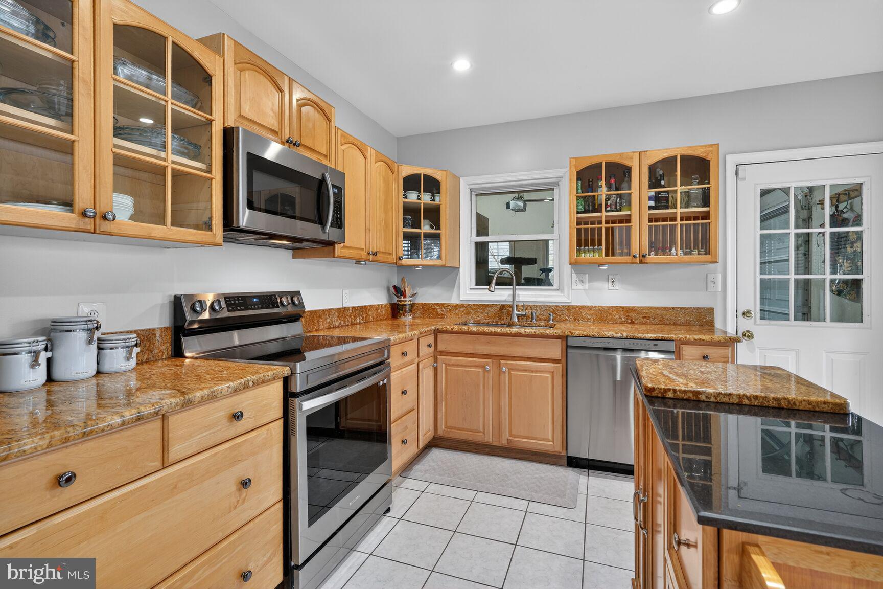 4406 Roundhill Road Alexandria, VA 22310 - Photo 11 of 48 a kitchen with stainless steel appliances granite countertop a stove top oven a sink dishwasher a dining table and chairs with wooden floor
