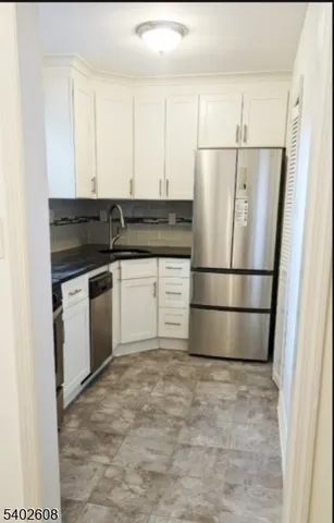 a kitchen with stainless steel appliances granite countertop a refrigerator sink and white cabinets