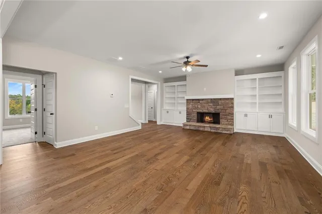 an empty room with wooden floor fireplace and window