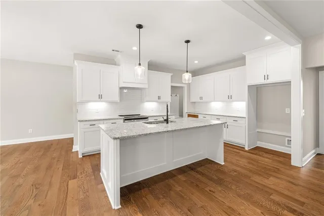 a open kitchen with stainless steel appliances granite countertop a sink a stove and a wooden floors