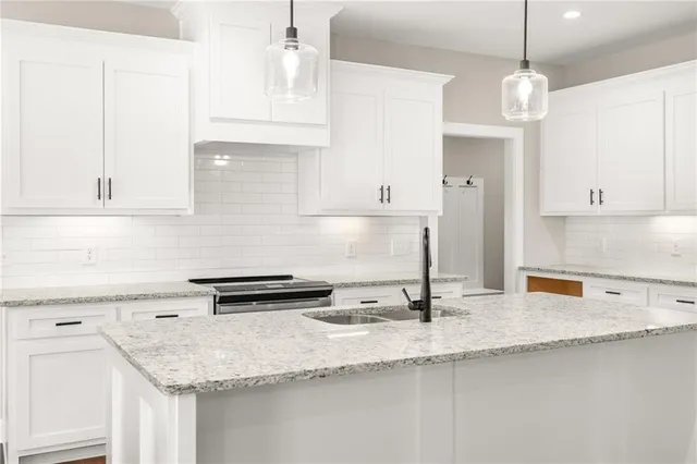 a kitchen with granite countertop a sink a stove and cabinets